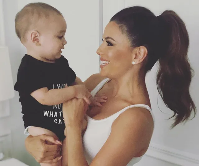 Woman holding a smiling baby in her arms, both looking at each other affectionately.