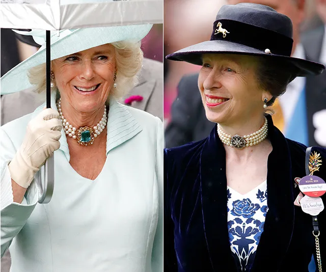 Two women in elegant outfits and hats, both wearing pearl chokers, smiling at an outdoor event.