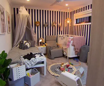 Modern nursery with black and white striped walls, a crib, toys, and cozy seating.