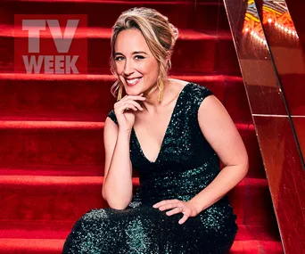 Eve Morey, in a sparkling black dress, smiles while sitting on red carpeted stairs for TV Week photo shoot.