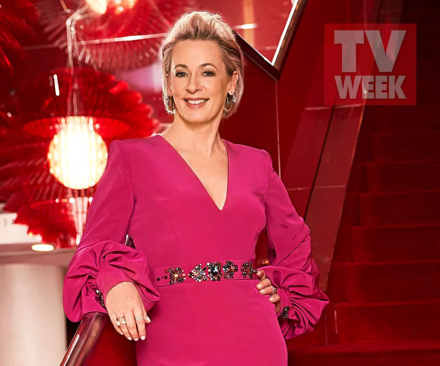 A woman in a pink dress on a red staircase, smiling, with TV WEEK logo in the background.