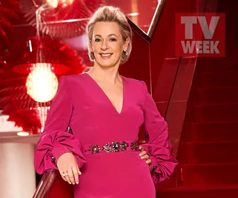 A woman in a pink dress on a red staircase, smiling, with TV WEEK logo in the background.
