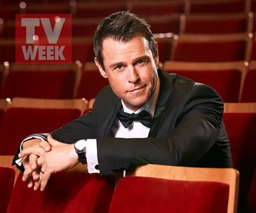 Man in a tuxedo sitting in an auditorium with "TV WEEK" visible in the background.