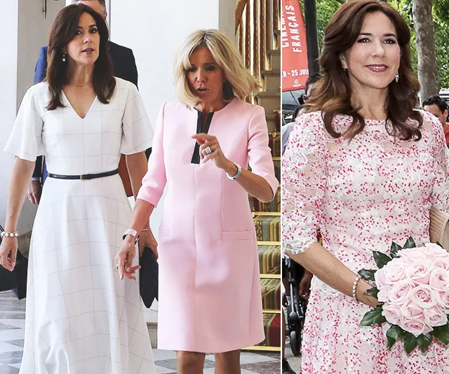 Princess Mary in white and floral dresses holding roses, walking with a woman in pink.