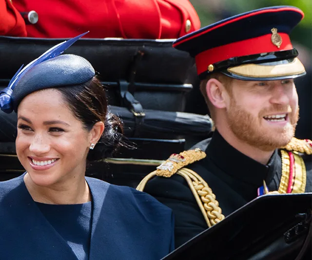 Royal couple smiling in a carriage, attending a formal event; Prince in uniform and Duchess in navy outfit and hat.
