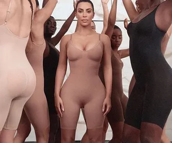 Women in shapewear bodysuits standing confidently in a diverse group.