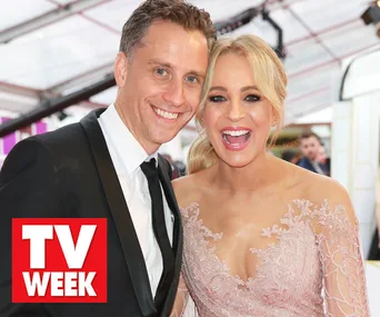 A man in a suit and a woman in a floral lace dress smile on the Logies 2019 red carpet.