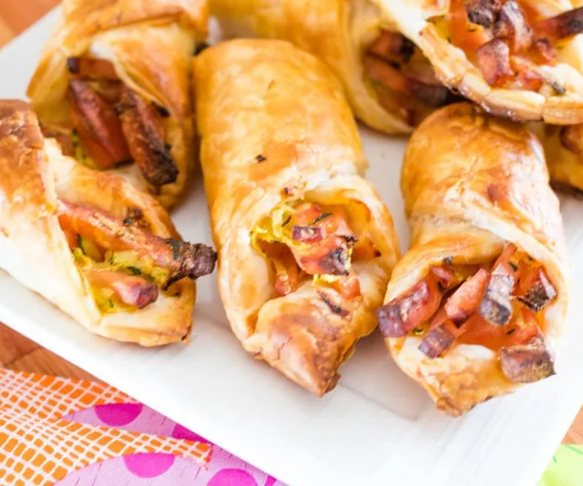 Golden puff pastries filled with hidden veggies and carrots on a white plate.