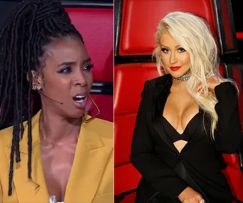 Two women seated in red chairs, one wearing a yellow jacket and the other in a black outfit with long blonde hair.