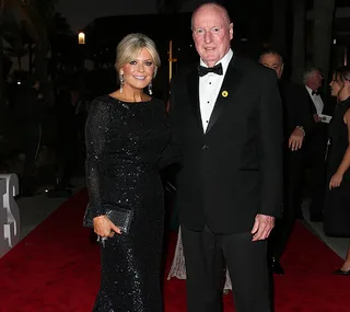 A man and a woman in formal attire on a red carpet at a nighttime event, posing for a photo.