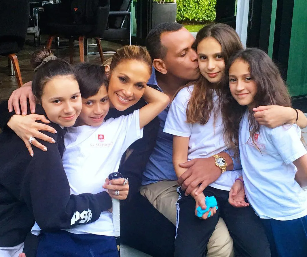Family group photo with a woman, man, and four children smiling and hugging in a casual setting.