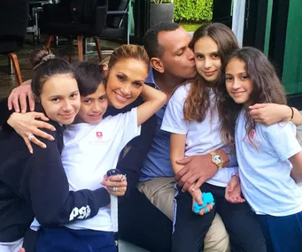 Family group photo with a woman, man, and four children smiling and hugging in a casual setting.