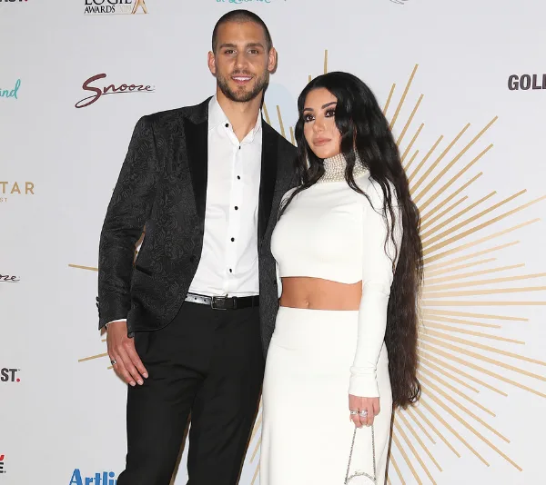 Couple posing together on a red carpet at an event, wearing formal attire.