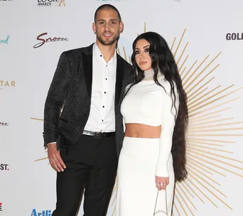 Couple posing together on a red carpet at an event, wearing formal attire.