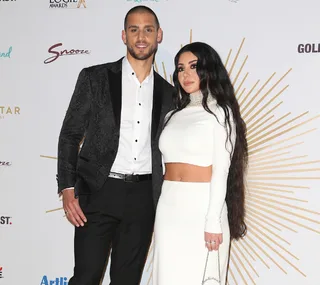 Couple posing together on a red carpet at an event, wearing formal attire.