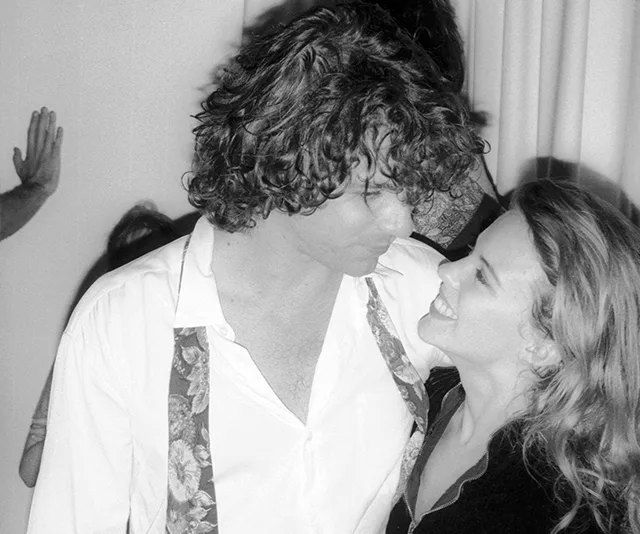 Two people share a tender moment, smiling and gazing into each other's eyes.