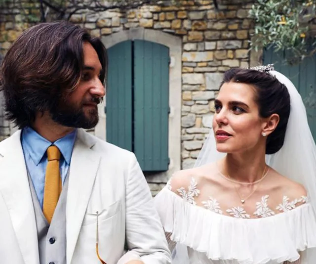 A bride and groom look at each other, with a stone building in the background.