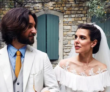 A bride and groom look at each other, with a stone building in the background.