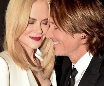A couple smiling and leaning in close to each other, both with closed eyes and content expressions.