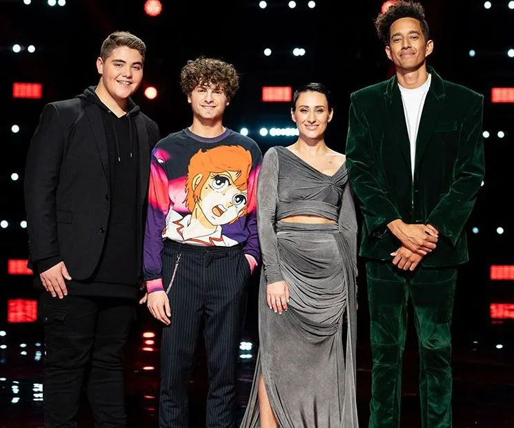 Four "The Voice 2019" finalists stand together on stage, smiling, with colorful lights in the background.