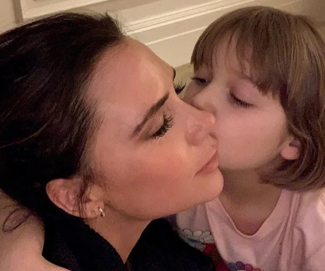 A woman receives a kiss on the cheek from a young child displaying affection.