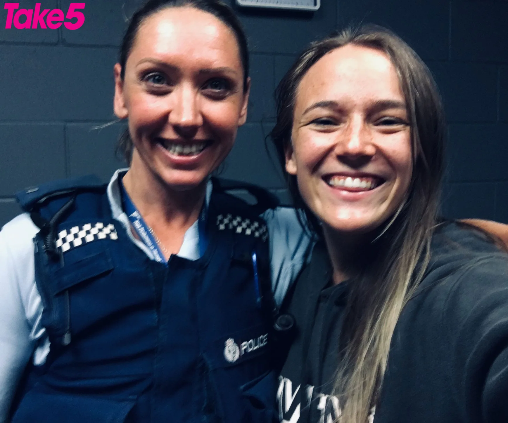 Two smiling women pose for a selfie; one is in a police uniform.