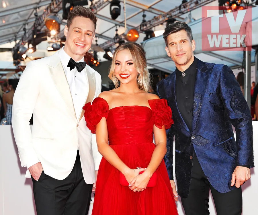 Three individuals pose in formal attire at a red carpet event under a canopy with TV WEEK signage in the background.