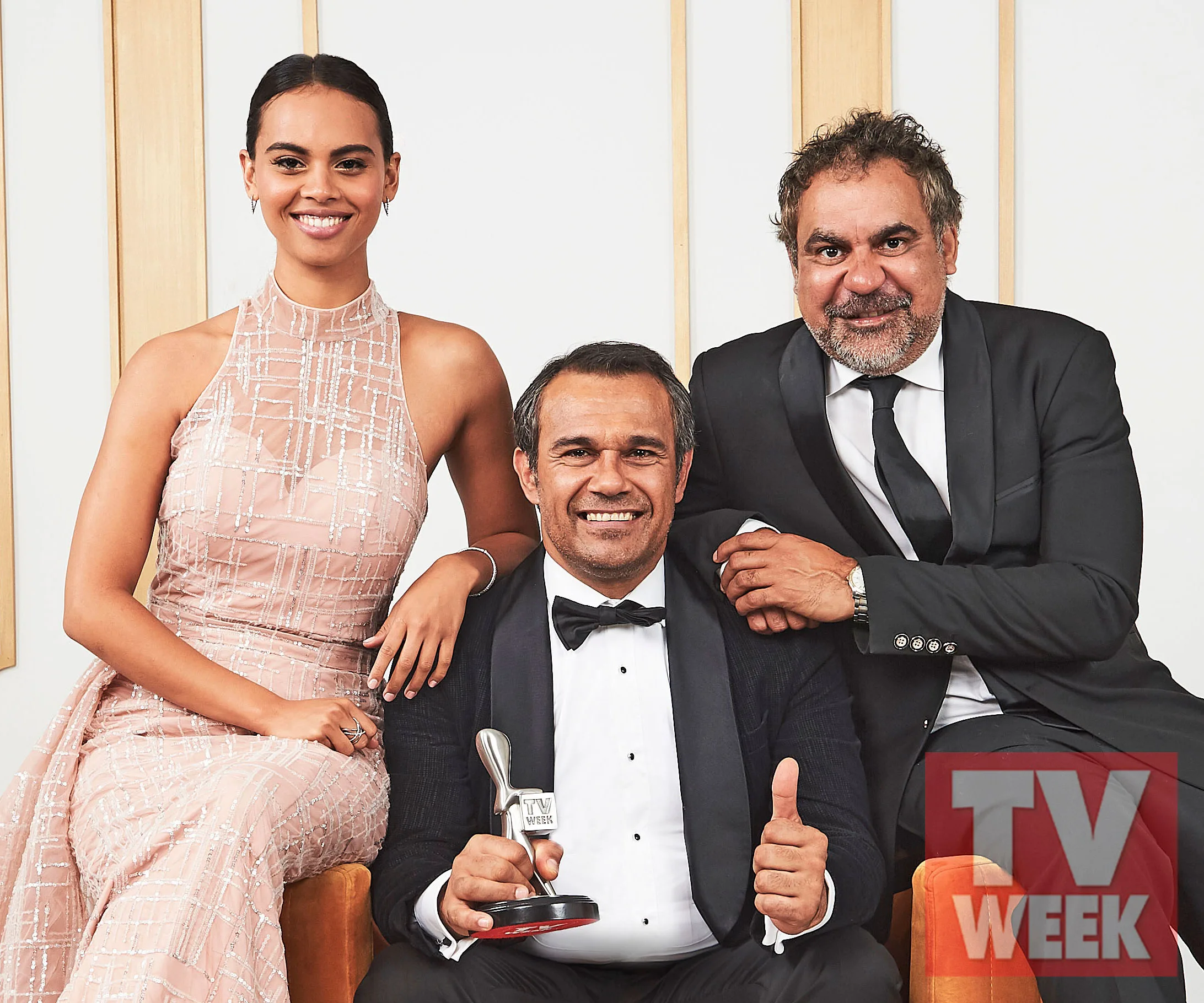 Three people from 'Mystery Road' celebrate a Logie win, one holding a trophy, dressed in formal attire with "TV WEEK" logo.