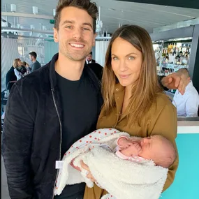 Couple smiling with a newborn wrapped in a blanket in a restaurant setting.