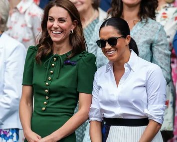 Two women smiling, one in a green dress and the other in a white shirt and sunglasses, standing in a crowd.