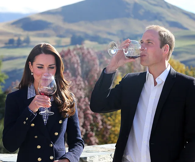 A man and woman enjoying wine outdoors with a scenic mountain backdrop.