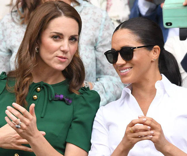 Two women sitting together, one in a green dress and the other in a white shirt and sunglasses, both smiling.