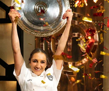 Chef holding MasterChef trophy amid confetti celebration.