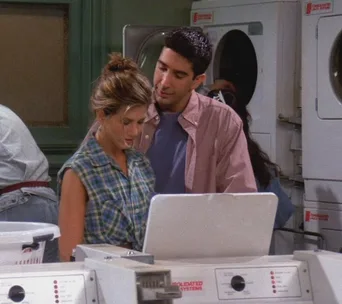 Couple in a laundromat, wearing casual clothes, with washing machines in the background.