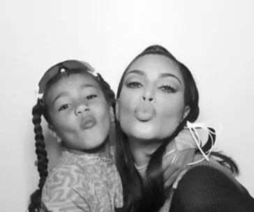Black and white photo of two individuals posing with pouty lips, wearing stylish outfits.