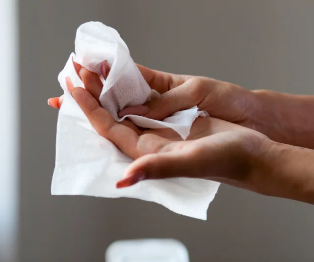 "Hands using a soft wet wipe for cleaning and refreshing skin."