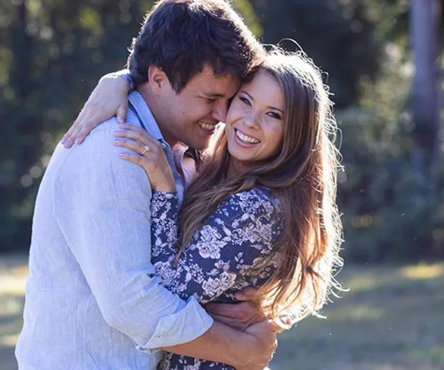 Couple embracing outdoors, both smiling and looking happy.