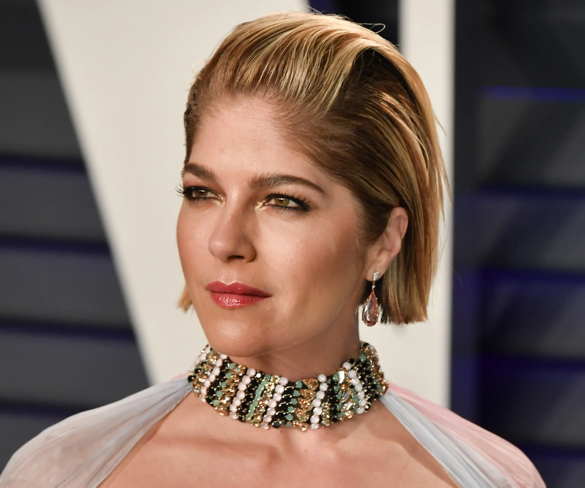A woman with short hair and jeweled choker at a formal event.