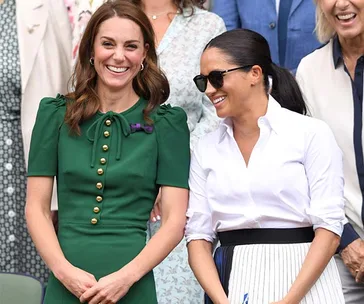 Two women smiling outdoors; one in a green dress, the other in a white blouse and sunglasses.