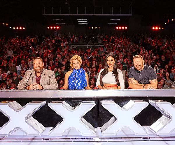 Judges seated at the "Australia's Got Talent" panel with an audience in the background.