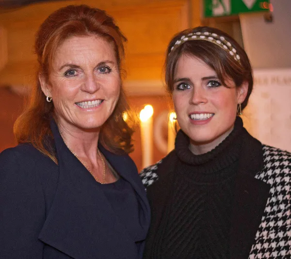Two women smiling and standing together in a warmly lit setting.