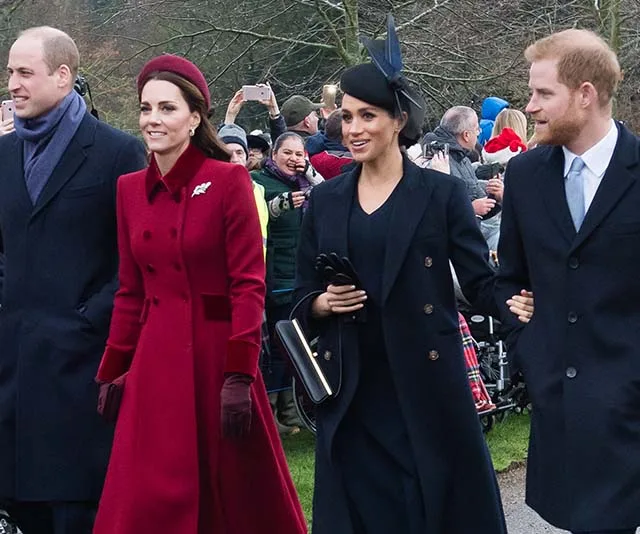 Group of people in formal attire walking outdoors, with a gathered crowd in the background.