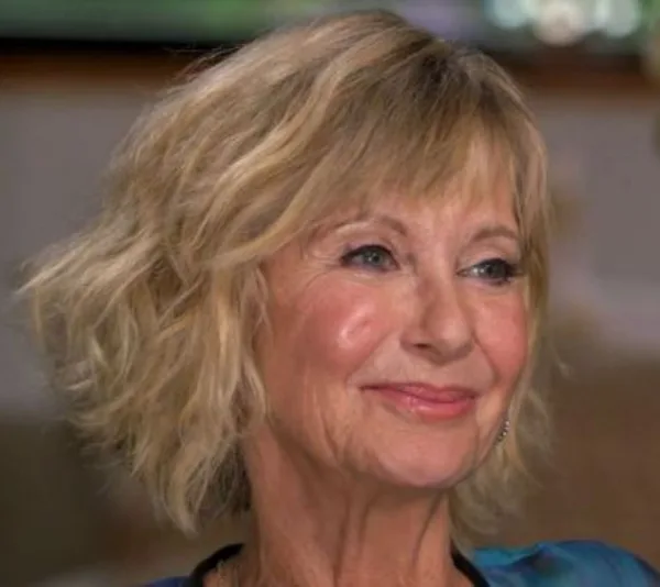 A person with short blonde hair smiling during an interview.
