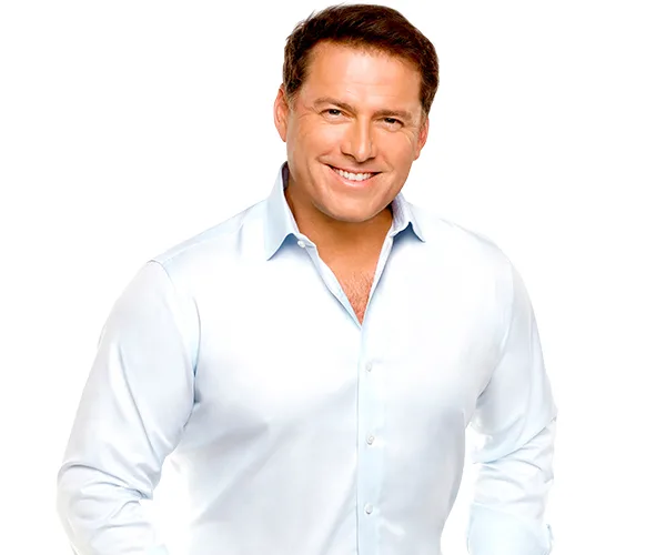 Man in a white shirt smiling with hands on hips against a white background.