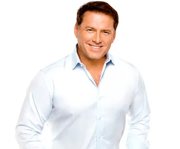 Man in a white shirt smiling with hands on hips against a white background.