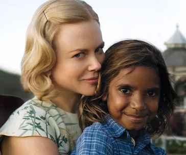 Blonde woman and young boy embracing outdoors, both smiling, scene from "Australia" movie featuring characters Lady Sarah and Nullah.