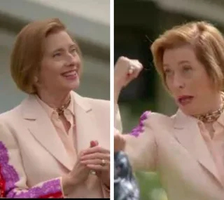 "Blonde woman in a pale suit making animated gestures outdoors."