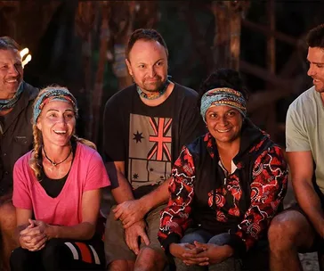 Group of five people sitting outdoors at a tribal council in Survivor, wearing colorful clothes and buffs.