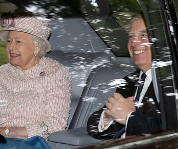 Queen and Prince Andrew in a car at Balmoral, both smiling, with trees reflected on the window.