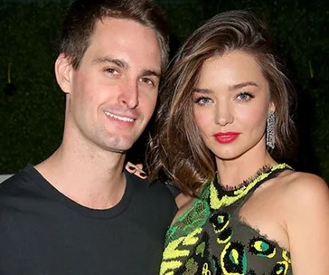 Two people smiling, one wearing a patterned dress.